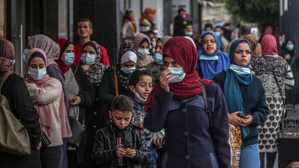 epa08867655 Palestinians wearing protective face masks walk in the market amid the ongoing coronavirus COVID-19 pandemic in Gaza City, 06 December 2020. The Ministry of Interior in Gaza City announced new measures as the number of new infections with the coronavirus increases, which are the closure of schools, universities, mosques, and government ministries until further notice, and work from six in the morning until six in the evening only, and a comprehensive closure on Friday and Saturday of every week.  EPA/MOHAMMED SABER