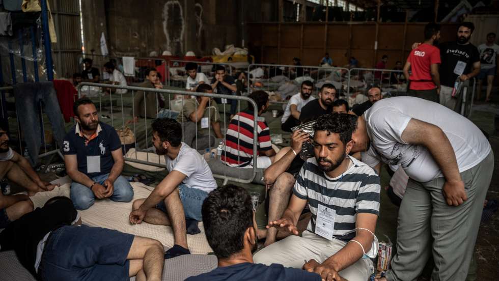 epa10692180 Survivors of a ship sit inside warehouse at the port town, after a boat carrying dozens of migrants sank in international waters in the Ionian Sea, in Kalamata, southwest of Athens, Greece, 15 June 2023. A total of 104 individuals were rescued, while 79 bodies were recovered, after a fishing boat capsized in international waters some 47 nautical miles southwest of the Peloponnese coast and the town of Pylos.  EPA/Angelos Tzortzinis / POOL HUNGARY OUT