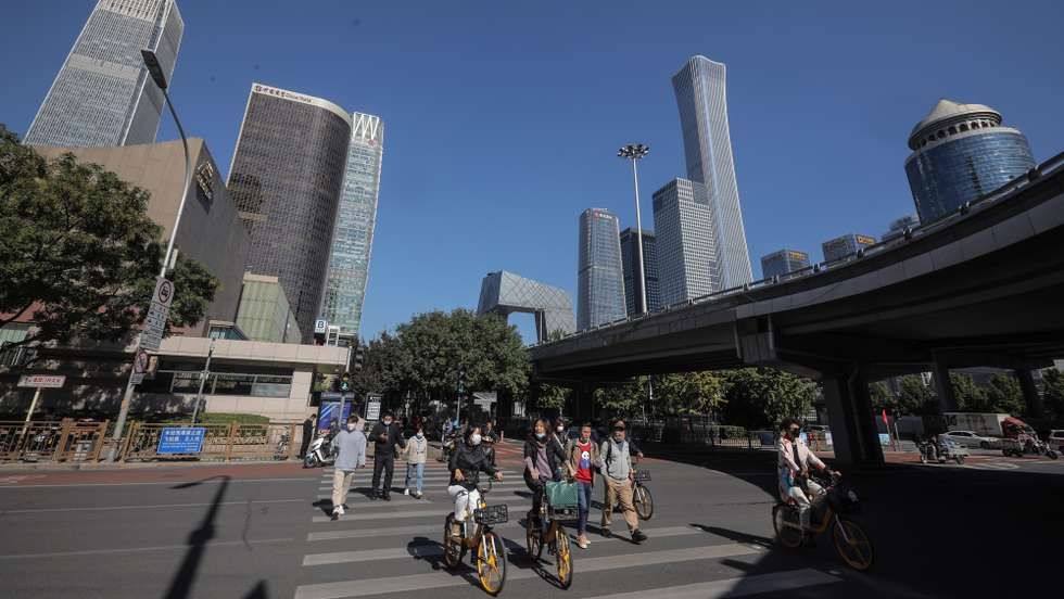 epa09529483 People walk and ride bicycles in the central business district (CBD) in Beijing, China, 17 October 2021 (issued 18 October 2021). China's gross domestic product (GDP) rose 4.9 percent year on year in the third quarter of 2021, according to data from the National Bureau of Statistics (NBS) issued on 18 October 2021.  EPA/WU HONG