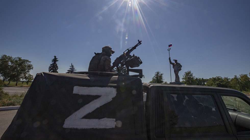 epa10009665 A picture taken during a visit to Mariupol organized by the Russian military shows a Russian serviceman in a vehicle with letter 'z' guards on the road in front of the monument of steel worker with Russian National flag at the entrance to the city of Mariupol, Donetsk region, Ukraine, 12 June 2022. On 24 February Russian troops entered Ukrainian territory starting a conflict that has provoked destruction and a humanitarian crisis. According to the UNHCR, more than six million refugees have fled Ukraine, and a further 7.7 million people have been displaced internally within Ukraine since.  EPA/SERGEI ILNITSKY