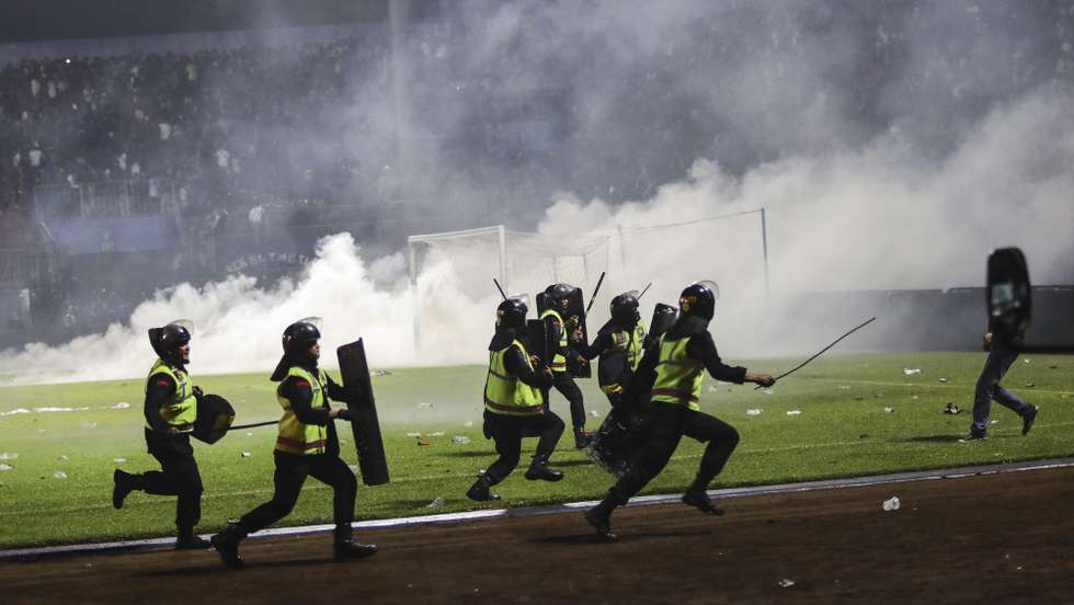 epa10218885 Police officers runs as they try to stop soccer fans from entering the pitch during a clash between fans at Kanjuruhan Stadium in Malang, East Java, Indonesia 02 October 2022. At least 127 people including police officers were killed mostly in stampedes after a clash between fans of two Indonesian soccer teams, according to the police.  EPA/H. PRABOWO