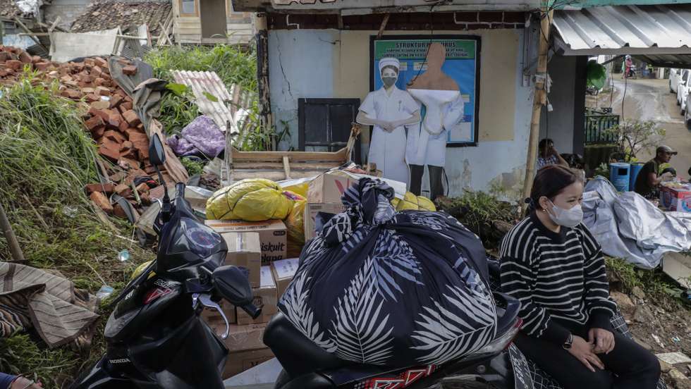 epa10329409 A woman sits next to her belongings at a village affected by the 5.6 magnitude earthquake in Cianjur, West Java, Indonesia, 26 November 2022. According to the National Disaster Management Authority (BNPB), at least 310 people killed and 24 missing after 5.6 magnitude earthquake hit southwest of Cianjur, West Java on 21 November 2022.  EPA/MAST IRHAM