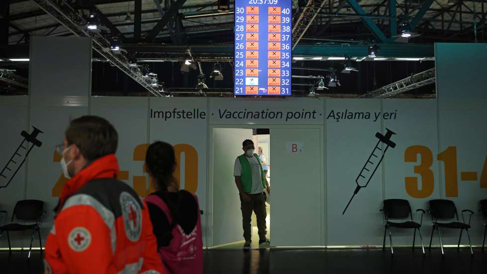 epa09407604 A vaccine center worker emerges from a door at the 'Long Night of Vaccinations' at the Arena mass vaccination center in Berlin, Germany, 09 August 2021. City authorities have organized several such events this week replete with DJs and party atmosphere in an effort to coax more young people to get vaccinated. Germany has made strong progress in its vaccination effort during the pandemic with almost 55 percent of the population now fully vaccinated, though the rate of new vaccinations has slowed in recent weeks.  EPA/Sean Gallup / POOL