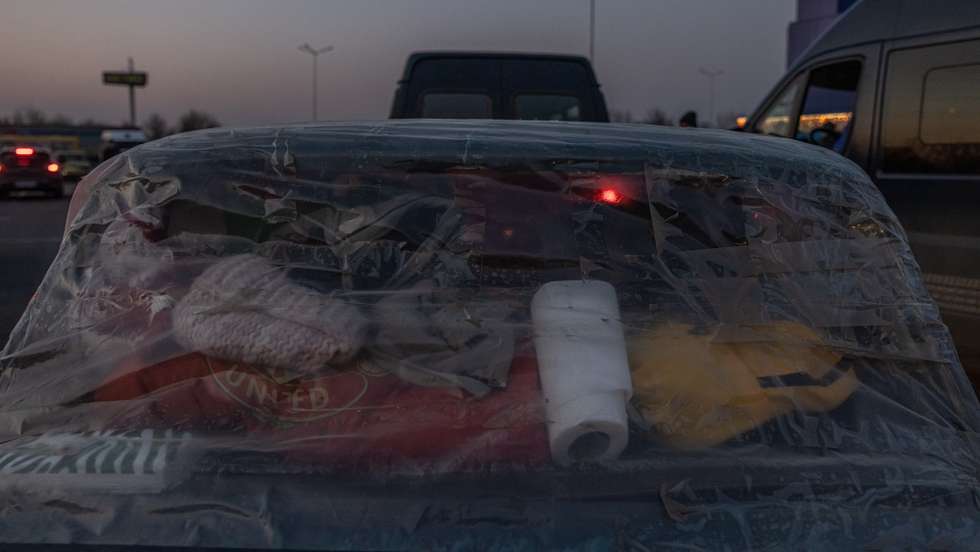 epa09850057 A car with plastic covering a back window parked as people who fled from the besieged by Russian military southeastern city of Mariupol and occupied Melitopol arrive at the evacuation point in Zaporizhzhia, Ukraine, 25 March 2022. Hundreds of people were evacuated on 25 March from the southeastern cities of Mariupol and Melitopol and arrived in Ukraine's controlled area by buses and their own cars. Almost 100,000 residents remain trapped and live in 'inhuman conditions' without food and water in the ruined city of Mariupol, amid Russia's 'constant shelling', Ukrainian president Volodymyr Zelenskyy says.  EPA/ROMAN PILIPEY