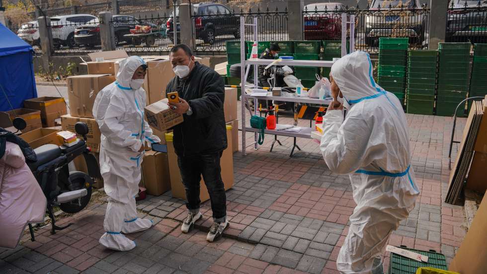 epa10333621 A volunteer health worker talks to a delivery man in front of a building under lockdown in Beijing, China, 28 November 2022. According to the National Health Commission, China has reported 36,525 new COVID-19 cases on 28 November, making it a record high for the fifth consecutive day as the country continues to contain outbreaks in several cities such as Guangzhou and Chongqing in the south.  EPA/WU HAO
