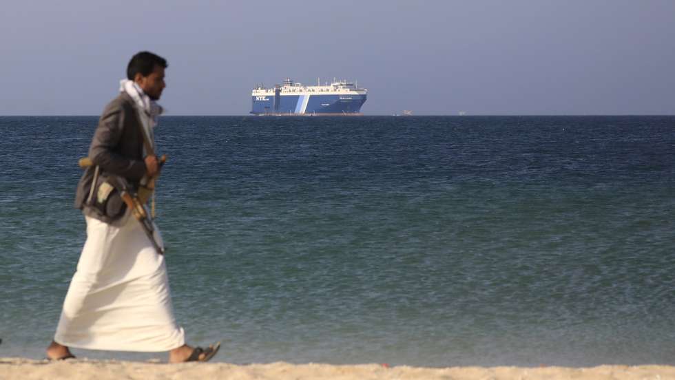 epaselect epa11014295 An armed Houthi fighter walks through the beach with the Galaxy Leader cargo ship in the background, seized by the Houthis offshore of the Al-Salif port on the Red Sea in the province of Hodeidah, Yemen, 05 December 2023 (issued 06 December 2023). Yemen's Houthis on 06 December 2023 claimed responsibility for the launch of the barrage of ballistic missiles toward Israel in support of the Palestinian people in the Gaza Strip, according to a statement by Houthis spokesman Yahya Saree. The Houthis vowed to continue their efforts to prevent Israeli ships from navigating in the Arabian and Red Seas, in retaliation for Israel's airstrikes on the Gaza Strip. Thousands of Israelis and Palestinians have died since the militant group Hamas launched an unprecedented attack on Israel from the Gaza Strip on 07 October, and the Israeli strikes on the Palestinian enclave which followed it.  EPA/YAHYA ARHAB