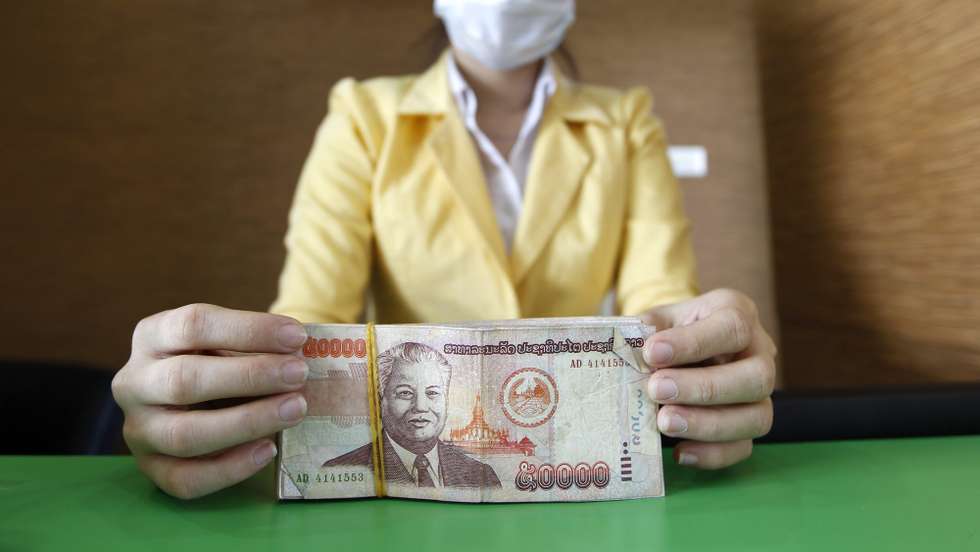 epa03455302 A Laotian bank teller displays Laos Kip notes at a currency exchange booth in Vientiane, Laos, 02 November 2012. The bank predicted Laos&#039; economy would grow 7.9 to 8.3 percent this year, fuelled by exports of hydroelectricity, copper and gold and steady increases in tourism and domestic consumption, among other things of Beer Lao, the country&#039;s most famous brand.  EPA/RUNGROJ YONGRIT