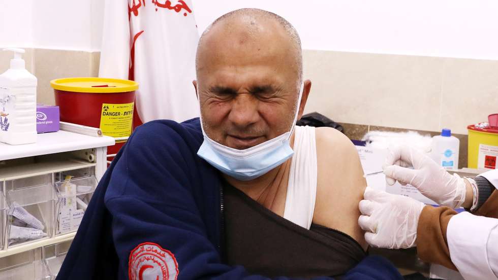 epa09095704 A Palestinian medical worker receives a coronavirus vaccine against COVID-19 at the Palestinian Red Crescent Hospital in the West bank city of Hebron, 25 March 2021. The Palestinian Authority received a limited number of coronavirus vaccine doses that will be used for vaccination of medical staff in Hebron.  EPA/ABED AL HASHLAMOUN