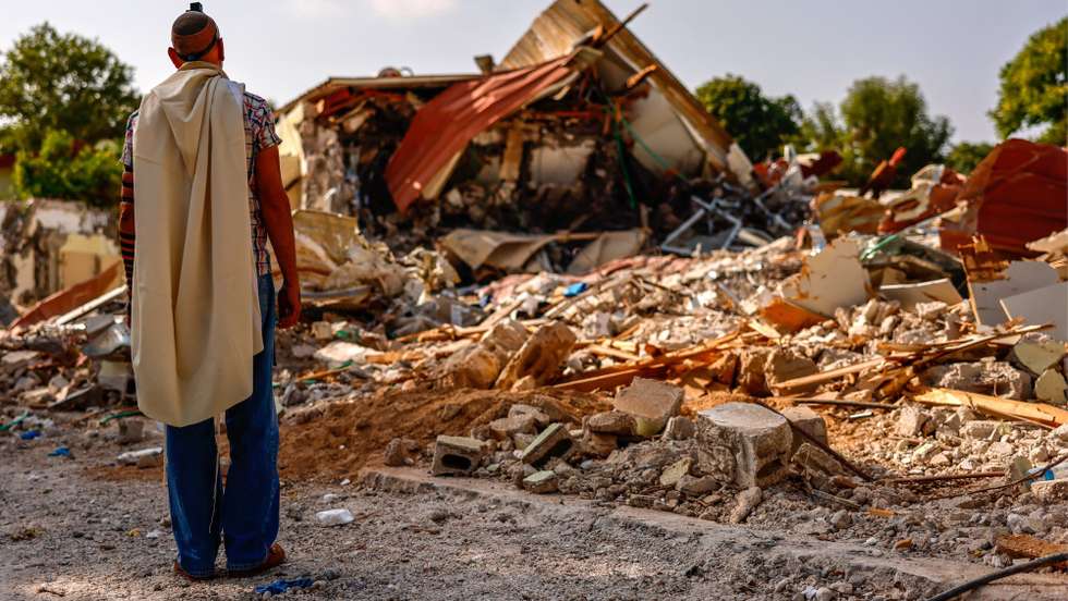 epa10932727 A man prays in front of destroyed houses in Kibbutz Be'eri, Israel, 22 October 2023. More than 4,500 Palestinians and 1,400 Israelis have been killed, according to the Israel Defense Forces (IDF) and the Palestinian health authority, since Hamas militants launched an attack against Israel from the Gaza Strip on 07 October.  EPA/HANNIBAL HANSCHKE