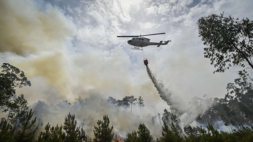 Um helicóptero de combate aos incêndios faz uma descarga de água sobre o fogo durante o incêndio florestal na aldeia do Lavradio, Ourém, 13 de julho de 2022. Dezasseis dos 18 distritos de Portugal continental estão hoje sob aviso vermelho, o mais grave, devido ao tempo quente, com mais de uma centena de concelhos em perigo máximo de incêndio rural. NUNO ANDRÉ FERREIRA/LUSA