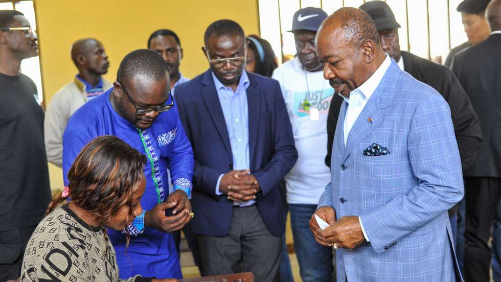 epa10821767 Gabonese President Ali Bongo Ondimba (R), speaks with an election official after casting his vote during the 2023 Gabonese general elections in Libreville, Gabon, 26 August 2023. A little under 850,000 registered voters out of a population of of 2.3 million are to decide whether to give President Ali Bongo Ondimba a third term.  EPA/STR