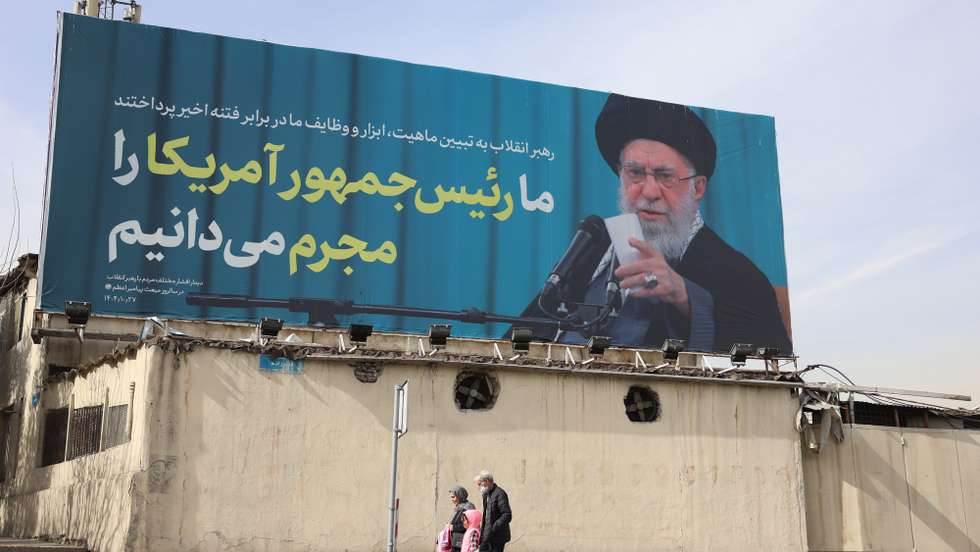 epa12699971 Iranians walk past a billboard with a photo of Iranian supreme leader Ayatollah Ali Khamenei and a sentence reading in Persian 'We know US president as a criminal following anti-government protests'  in a street in Tehran, Iran, 02 February 2026. Following the US President Donald Trump renewed threats of military action against Iran, Iranian supreme leader Ayatollah Ali Khamenei on 01 February 2026 warned that any military attack by the United States would spark a 'regional war'.  EPA/ABEDIN TAHERKENAREH