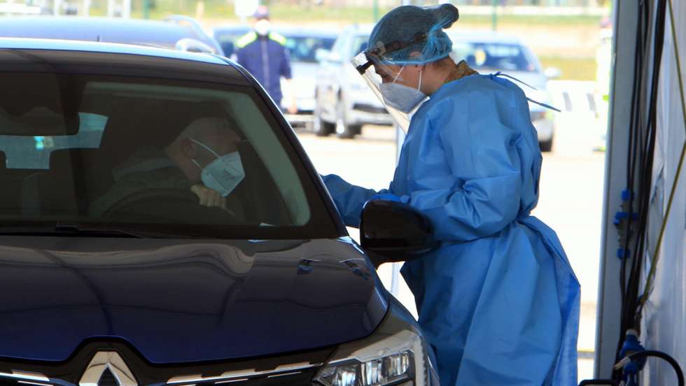 epa09076534 A Health worker wearing an overall and a protective mask performs swab tests on motorists queueing at the drive-through COVID-19 swab test set up in via Novara Trenno, in Milan, Italy, 15 March 2021. Milan started the first Drive Through for vaccines at the 8 lines built by the army in via Novara, at the moment, only two out of eight lines has been converted to a vaccination center, the other six are still for screening and swabs.  EPA/Paolo Salmoirago