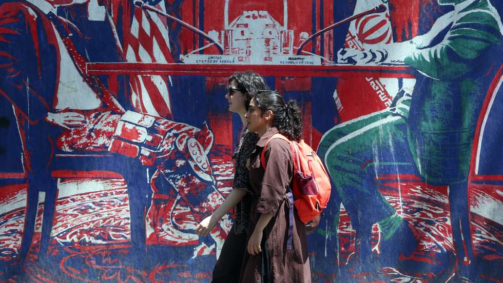epa13055976 Iranian girls walk past an anti-US mural (depicting an Iranian and US negotiation table) next to the former US embassy in Tehran, Iran, 22 June 2026. Leaders of the Iranian negotiation team, Mohammad Bagher Ghalibaf and Abbas Araghchi, left the Lucerne Summit in Switzerland after 18 hours of talks with the US, Pakistan, and Qatar.  EPA/ABEDIN TAHERKENAREH RESTRICTIONS: NO Access Israel Media/Persian Language TV Stations Outside Iran/Strictly No Access BBC Persian/VOA Persian/Manoto TV/Iran International TV. (As mandated by Iran's Directorate General for Foreign Media) --