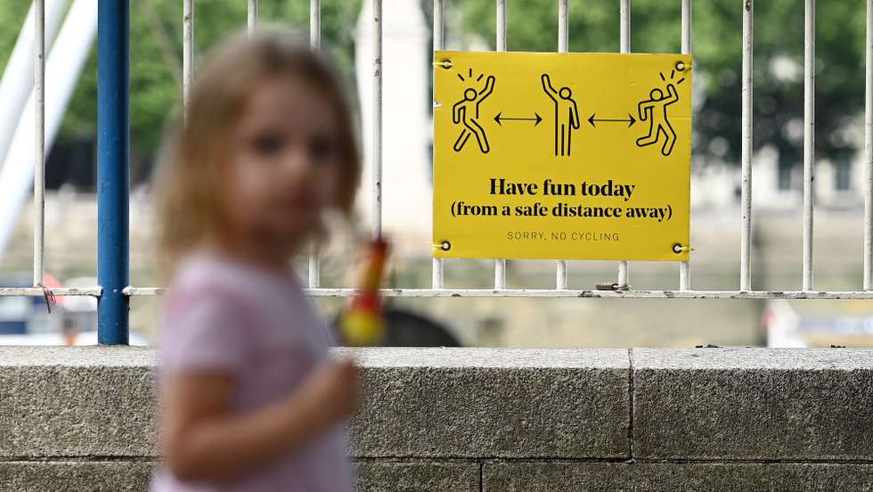 epa09272809 A child passes a social distancing sign along the Southbank in London, Britain, 15 June 2021. British Prime Minister Boris Johnson has announced on 14 June, a month long delay to lockdown easing regulations. The UK government is to delay for a further four weeks to full reopening due to a significant rise in Delta variant Covid-19 cases across England.  EPA/ANDY RAIN