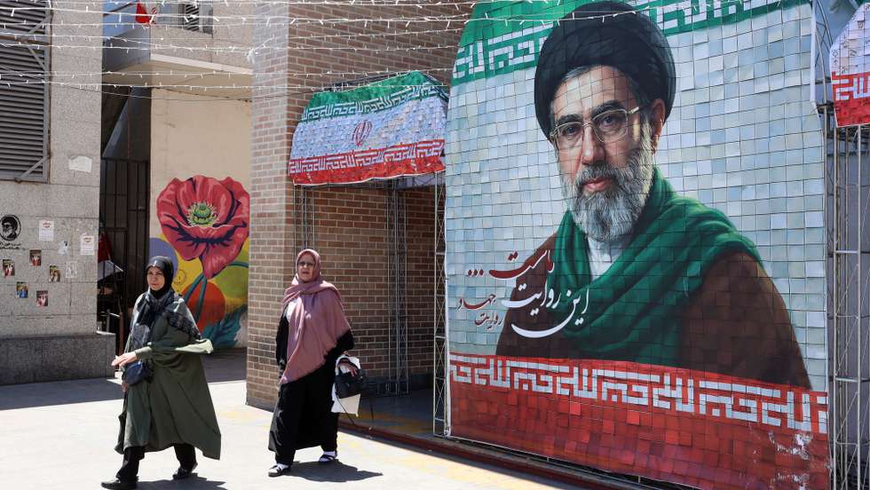 epaselect epa12970279 Iranians walk past a picture of Iranian supreme leader Ayatollah Mojtaba Khamenei in a street in Tehran, Iran, 18 May 2026. The conflict between Iran and the US continues as US President Donald Trump repeated threats of fresh military action against Iran.  EPA/ABEDIN TAHERKENAREH