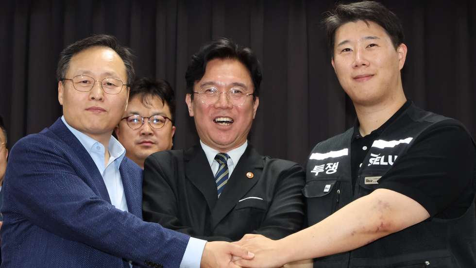 epa12979200 Yeo Myeong-gu (L), head of Samsung Electronics Co.'s device solutions division's people team, and Choi Seung-ho (R), chief of Samsung's largest labor union, hold hands with Labor Minister Kim Young-hoon at the Gyeonggi District Employment and Labor Office in Suwon, south of Seoul, South Korea, 20 May 2026, after reaching an agreement on a wage deal a day before the union's planned strike at the world's largest memory chipmaker. The labor union said it decided to hold off on plans for a strike and will put the tentative wage deal to a vote.  EPA/YONHAP / POOL SOUTH KOREA OUT