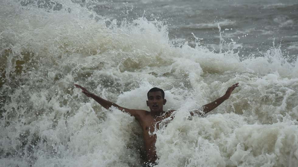 epa09356753 A youth gets splashed by a huge wave while swimming at Foreshore Estate beach in Chennai, India. 21 July 2021.  EPA/IDREES MOHAMMED