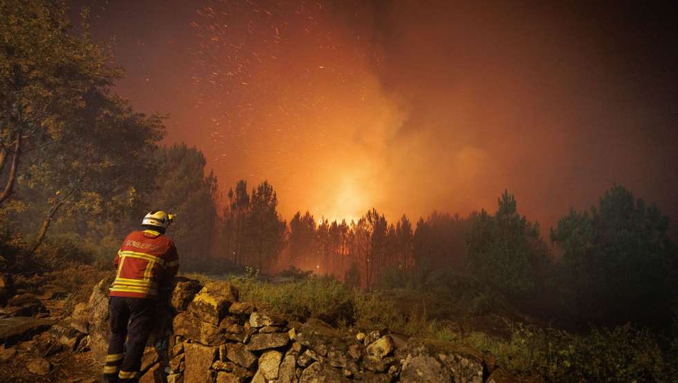 Um bombeiro observa as chamas durante o combate ao incêndio na aldeia de Escariz que se viu envolvida pelas chamas, esta tarde, em Vila Real, 21 de agosto 2022. PEDRO SARMENTO COSTA/LUSA