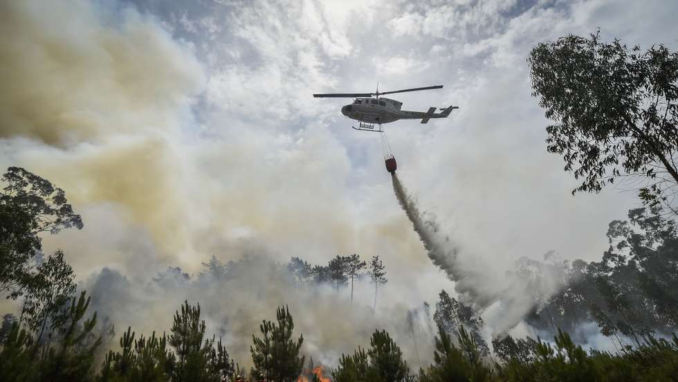 Um helicóptero de combate aos incêndios faz uma descarga de água sobre o fogo durante o incêndio florestal na aldeia do Lavradio, Ourém, 13 de julho de 2022. Dezasseis dos 18 distritos de Portugal continental estão hoje sob aviso vermelho, o mais grave, devido ao tempo quente, com mais de uma centena de concelhos em perigo máximo de incêndio rural. NUNO ANDRÉ FERREIRA/LUSA