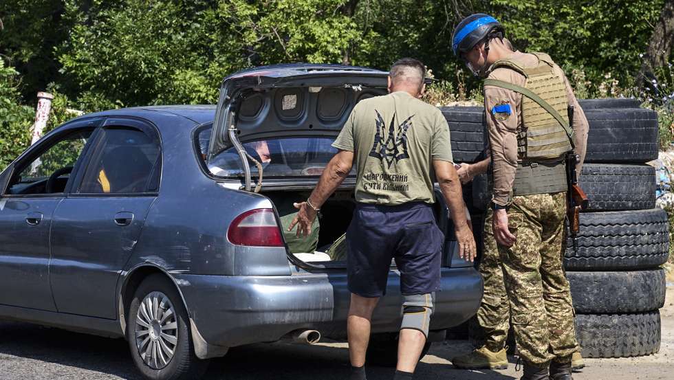 epa11497311 Ukrainian police and National Guard servicemen check vehicles at a checkpoint on the outskirts of Kharkiv, northeastern Ukraine, 26 July 2024. Ukrainian servicemen are deployed at checkpoints to control traffic, and inspect vehicles and luggage to prevent the entry of illegal cargo, weapons, sabotage groups, and illegal gangs. Kharkiv is located less than 30 kilometers from the Russian border and suburban villages in the north direction are regularly shelled by multiple rocket launchers. Russian troops entered Ukrainian territory in February 2022, starting a conflict that has provoked destruction and a humanitarian crisis.  EPA/SERGEY KOZLOV