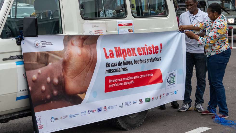 epa11587143 Workers install Mpox prevention banners on a Ministry of Health van in Kinshasa, Democratic Republic of Congo, 05 September 2024. The Democratic Republic of Congo received the first delivery of almost 100,000 doses of mpox vaccines. The country is at the epicenter of a mpox outbreak, declared a global public health emergency by the World Health Organization (WHO)in August.  EPA/CHRIS MILOSI