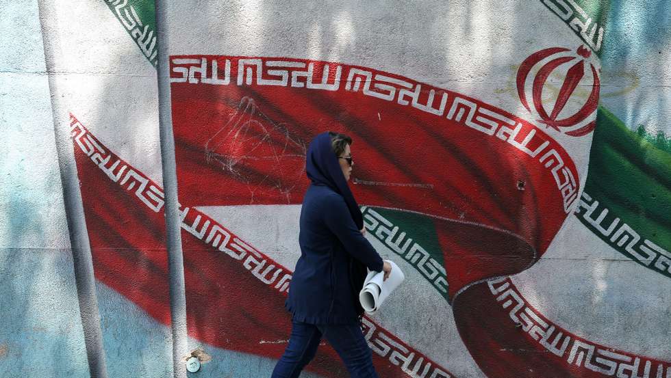 epa11547356 An Iranian woman walks past next to a wall painting of Iran's national flag on a street in Tehran, Iran, 13 August 2024. Tension remains high between Iran and Israel since late Hamas leader Ismail Haniyeh was killed in Tehran on 31 July 2024, as Iran's leader Ayatollah Khamenei had vowed for a 'harsh punishment' against Israel in retaliation over the killing of Haniyeh. US and EU administration asked Iran not to attack Israel.  EPA/ABEDIN TAHERKENAREH