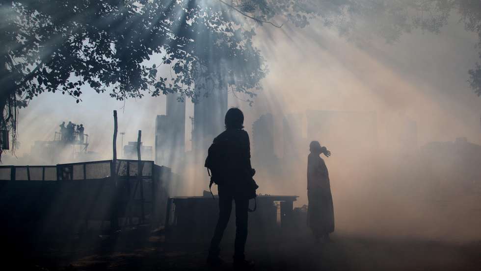 epa03589182 An Indian woman covers her face (R) during an anti-malaria fumigation in Mumbai, India, 18 February 2013. Municipal authorities have identified areas of the city where accumulated water offers a breeding ground for mosquitoes, encouraging a wider spread of malaria and dengue.  EPA/DIVYAKANT SOLANKI