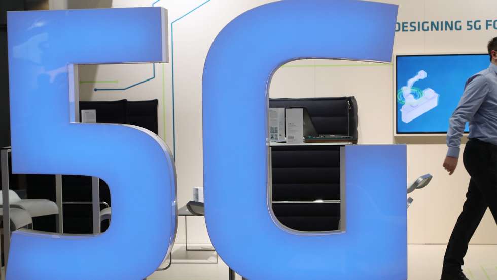 epa07475973 A man walks  behind a 5G logo at the Hannover Industry Fair (Hannover Messe) in Hanover, Germany, 31 March 2019. From 01 April to 05 April, 6,500 exhibitors from 75 countries show their products during one of the World's leading fairs for industrial goods. Main focus of the Hannover Messe 2019 is on Artificial Intelligence and the new mobile standard 5G.  EPA/FOCKE STRANGMANN
