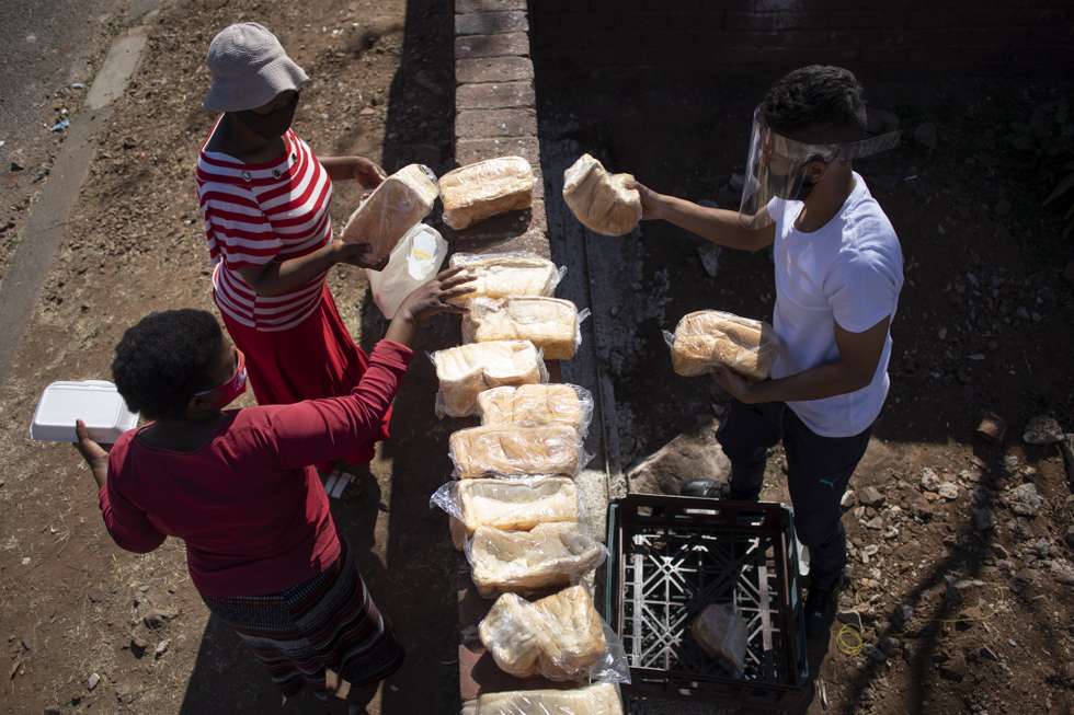 epa08578623 Women receive bread at a food handout during the Eid al Adha at the 'Hunger Has No Religion' feeding scheme, in Johannesburg, South Africa, 01 August 2020. The local Muslim community spent the time they would have shared with family celebrating Eid al-Adha by feeding hundreds who are facing food insecurity due to the effects of the 5th month of pandemic lockdown. Food insecurity is one of the main issues facing the country since the start of coronavirus pandemic lockdown.  EPA/KIM LUDBROOK
