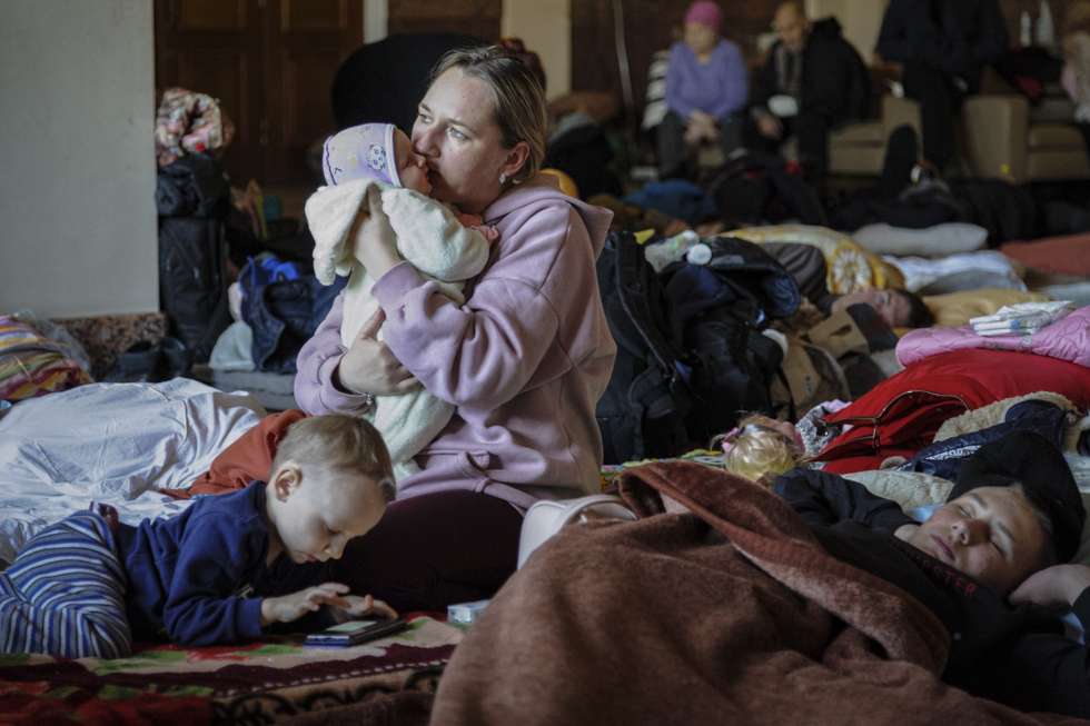 epaselect epa09817799 A woman with her children wait for the train in the railway station as they try to flee the war in Lviv, Ukraine, 11 March 2022. Russian troops entered Ukraine on 24 February 2022, prompting a series of severe economic sanctions imposed by Western countries on Russia.  EPA/MYKOLA TYS