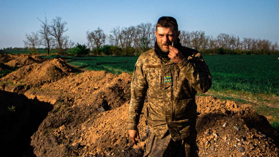 Military soldier takes a break and smokes a cigarette.
