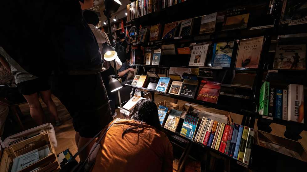 A woman browses the books on a bottom shelf.Crowds of