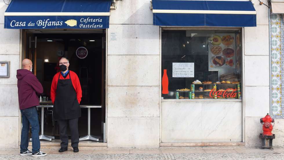 Men talking outside a restaurant at Figueira Square, as