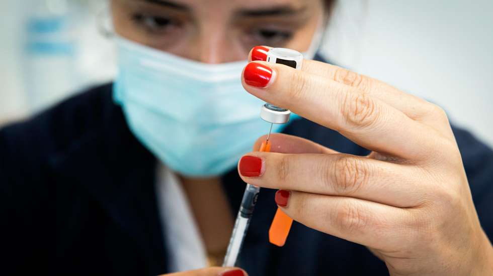 A nurse fills a syringe with the Cominarty vaccine.The