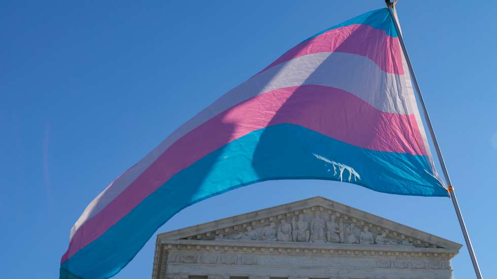 Manifestantes em apoio à participação de atletas transgénero em competições femininas agitam uma bandeira do orgulho transgénero em frente ao Supremo Tribunal dos EUA, em Washington D.C, em 2026
