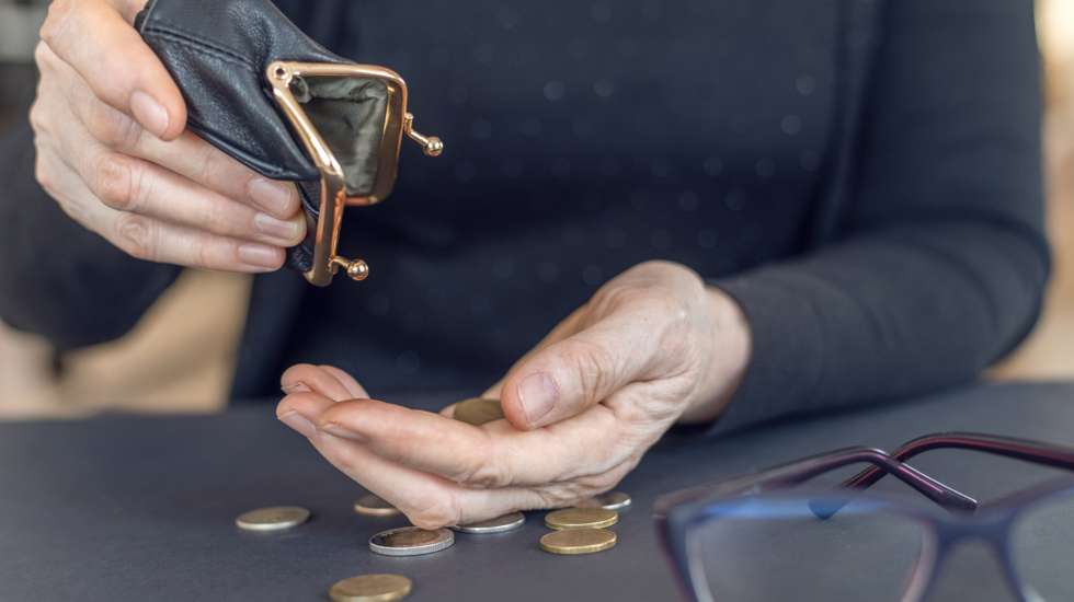 An elderly woman holds an open empty wallet in her hands, the concept of poverty, pension