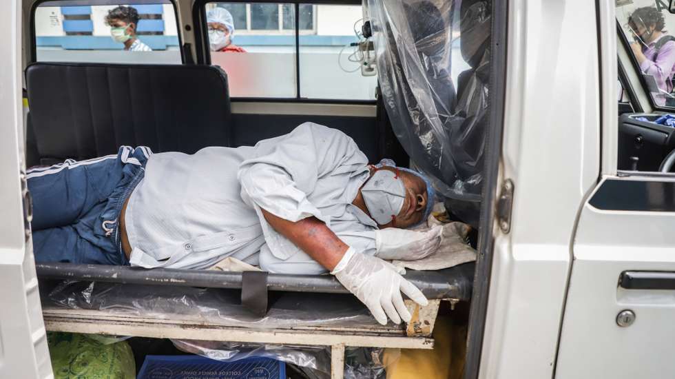 A patient groans in an ambulance outside of a COVID-19 care