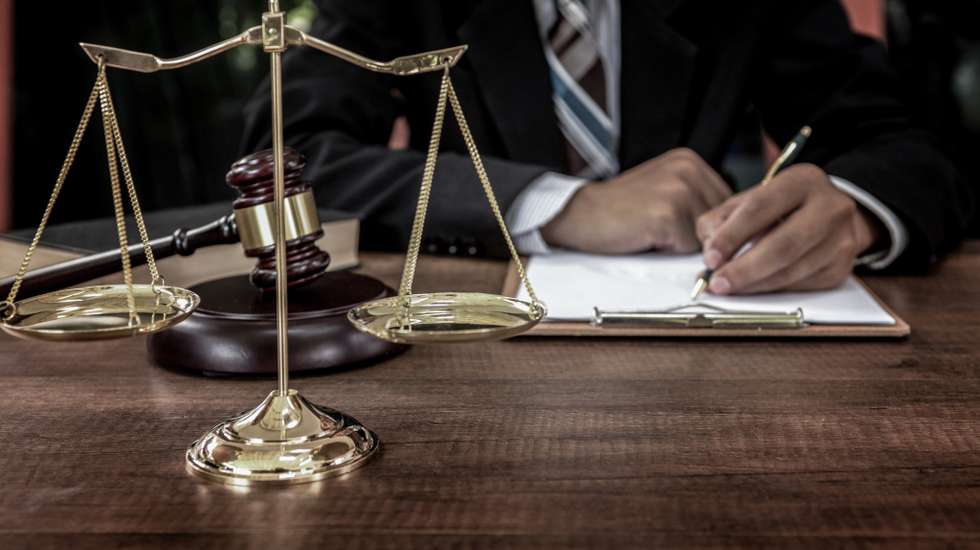 Tribunal attorney lawyer working with documents and wooden judge gavel on table in courtroom.