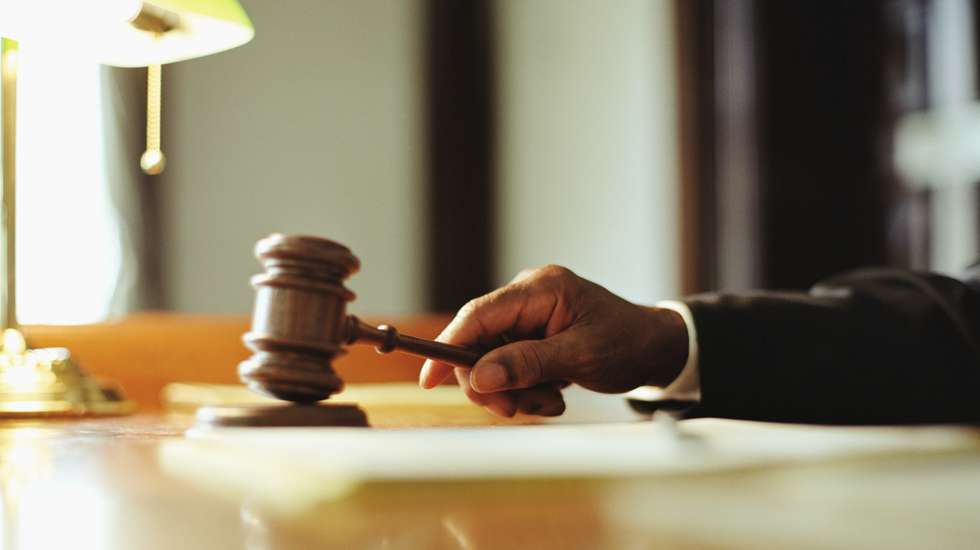 Male judge striking gavel in courtroom, close-up