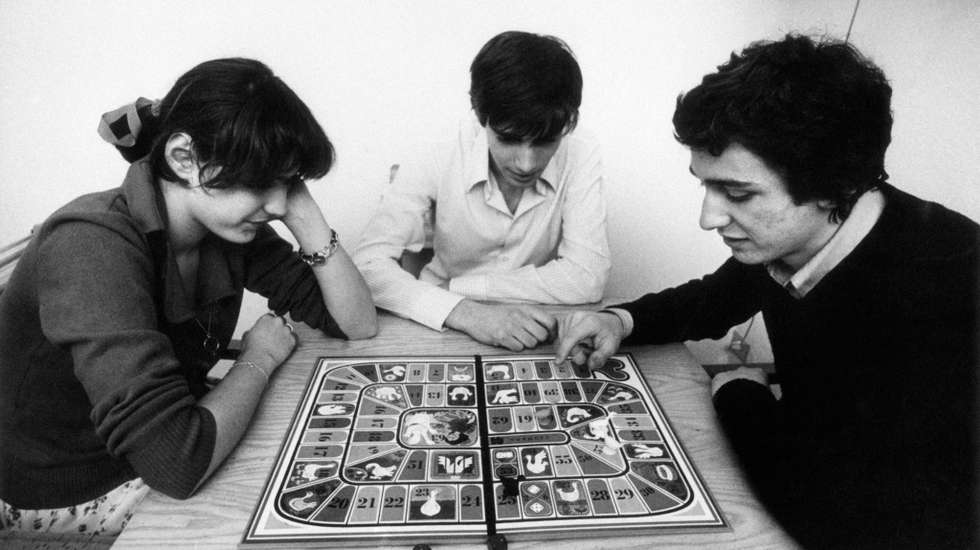 A girl and two boys playing the Game of the Goose