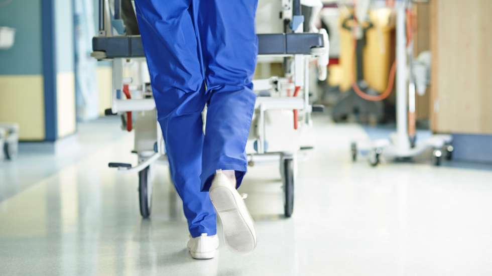 Legs of medic running with gurney along hospital corridor