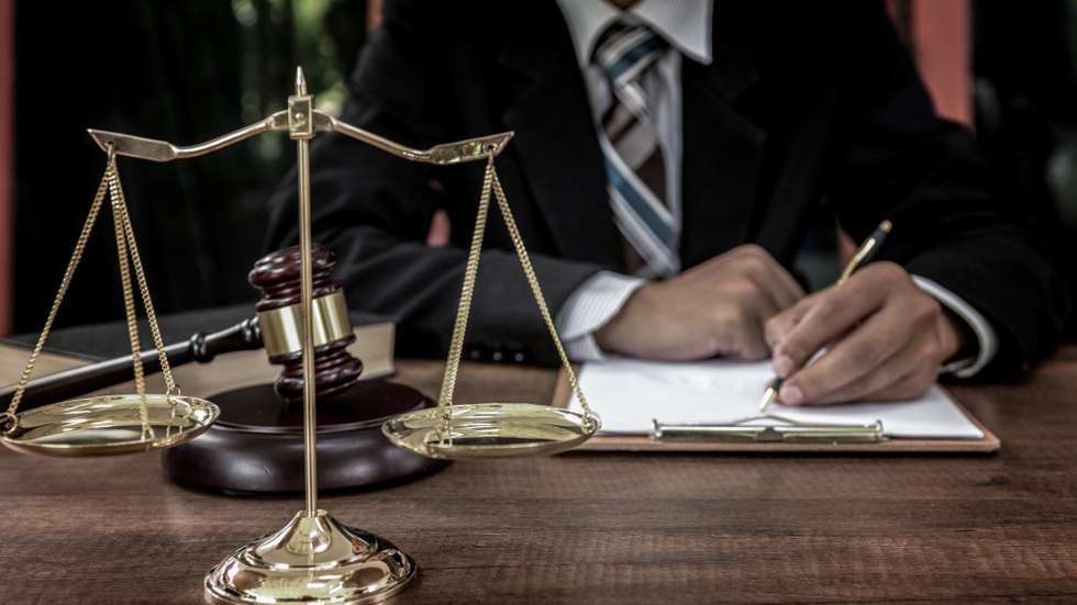 Tribunal attorney lawyer working with documents and wooden judge gavel on table in courtroom.