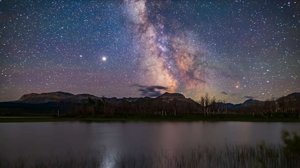 The galactic core area of the Milky Way over Maskinonge Pond in Waterton Lakes National Park, Alberta. Jupiter is the bright object at left, with Saturn dimmer to the left (east) of Jupiter. In the summer of 2020 the two planets were close together in the