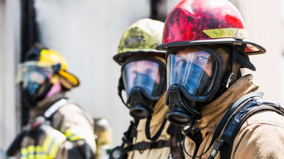 Three firefighters wearing oxygen masks