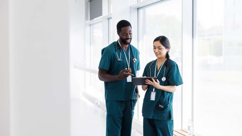 Two doctors in hospital hallway discussing electronic  patient record