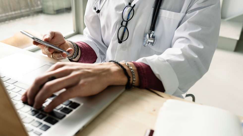 close-up of a female doctor using computer and smartphone