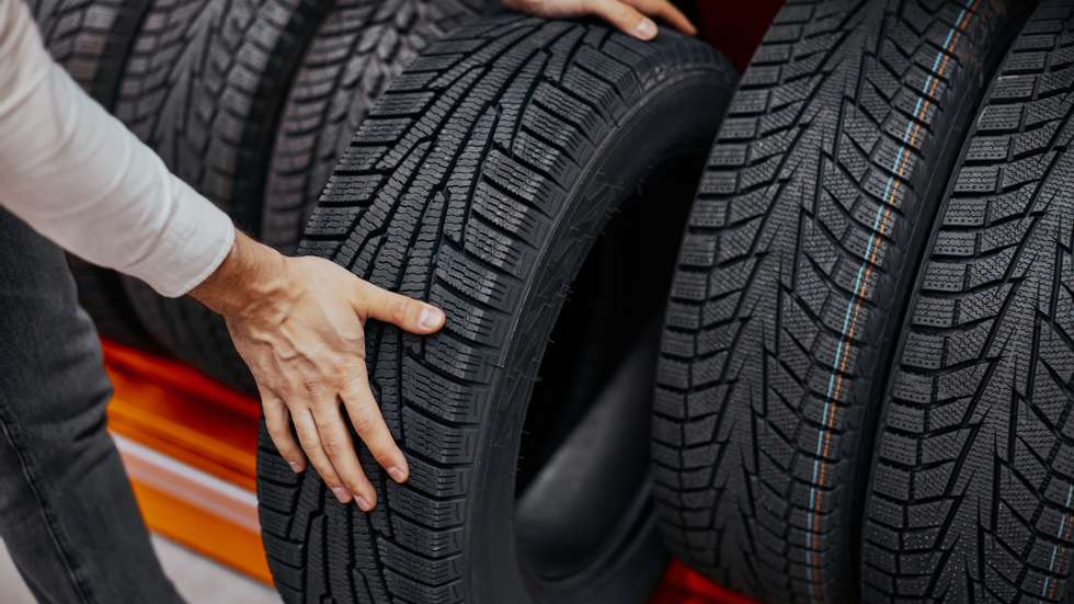 Close-Up Of A Man&#039;s Hand With Car Tires In Auto Shop