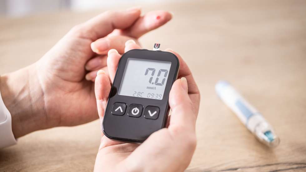 Close-up of woman hands measuring glucose level blood test with glucometer.