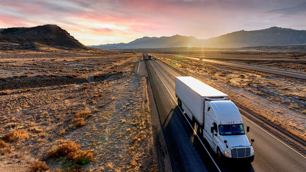 White Semi-Trailer Truck Heading down a four-lane Highway at Dusk
